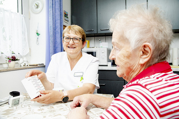 Pflegerin am Küchentisch mit Patientin